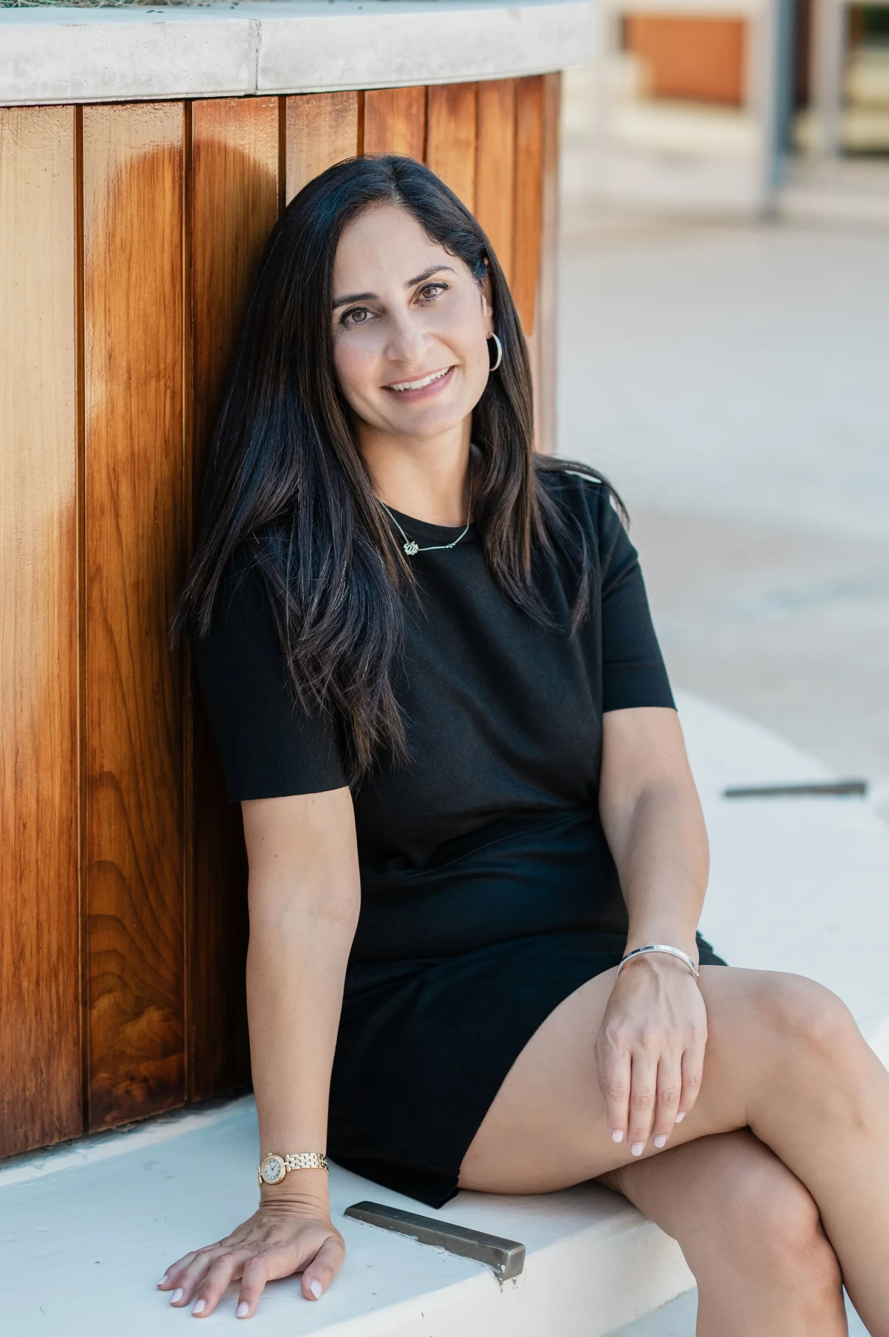 Pardis Mahdavi seated outdoors against a wooden bench, smiling.